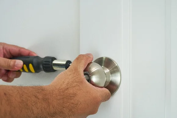 Person bringt Türklinke mit Schraubenzieher an